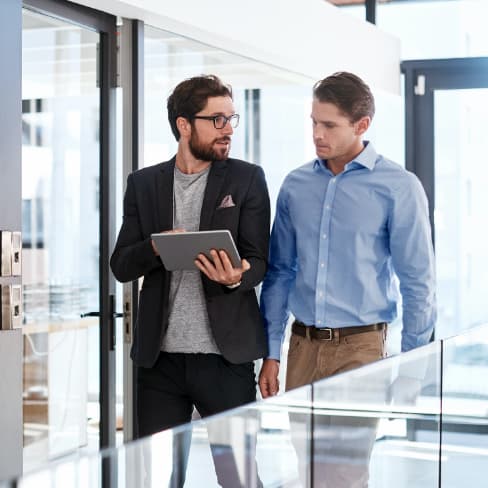 2 men conferring while walking through office