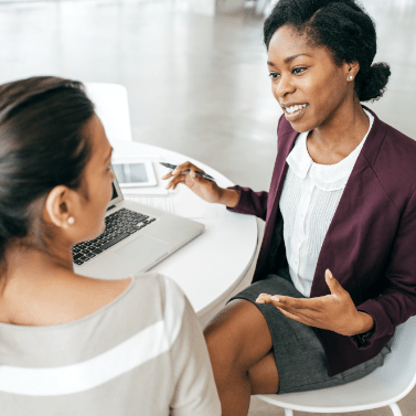 2 femmes discutant devant un poste de travail informatique